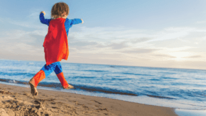Child in cape running along beach
